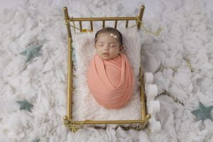 A baby girl is laying in a crib with stars on it.