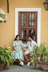 A couple sitting on a bench in front of a yellow building.