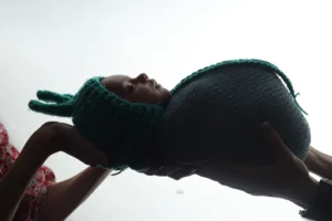 A couple holding a baby in a knitted hat.