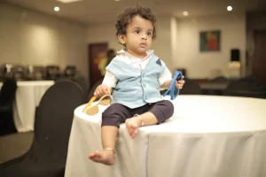 A baby sitting on top of a table holding a toy.