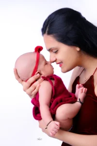 A woman holding a baby in a red dress.