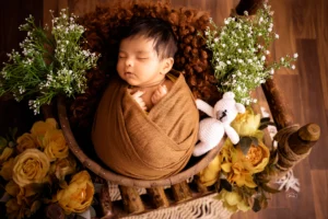 A baby sleeping in a basket with flowers.