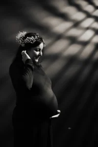 A pregnant woman in black and white with a crown on her head.