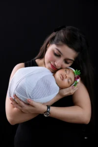 A woman is holding a baby on a black background.