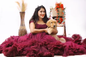 A woman in a burgundy dress holding a golden retriever.