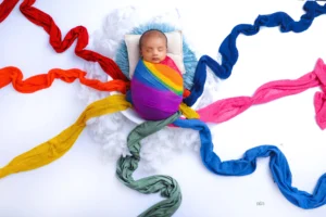 A child wrapped in colorful ribbons in a cloud-like tub.
