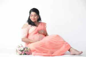 A pregnant woman in a pink sari posing on the floor.