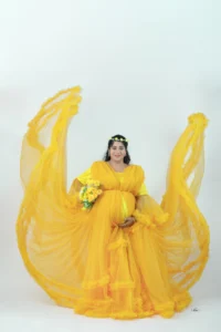 A pregnant woman in a yellow dress posing.
