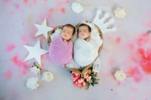 Two newborn babies in a heart shaped basket.